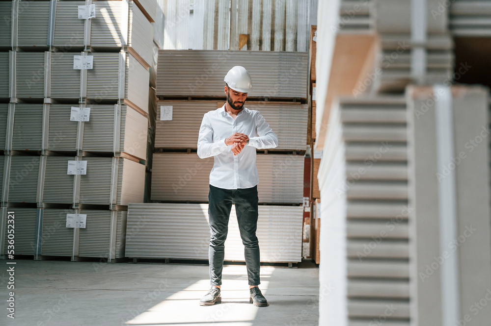 Serious manager in formal clothes. Storage worker is in the warehouse with bunch of products Serious manager in formal clothes. Storage worker is in the warehouse with bunch of products