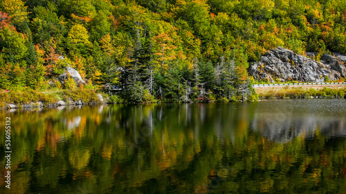 Fototapeta Naklejka Na Ścianę i Meble -  Autumn colored trees with reflections in water near mountain road