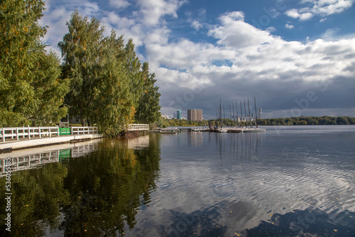 Beautiful autumn landscape in the park. City Park. Sunny sunset light. Beautiful reflection in the water. Colorful trees. Blue sky with clouds. photo