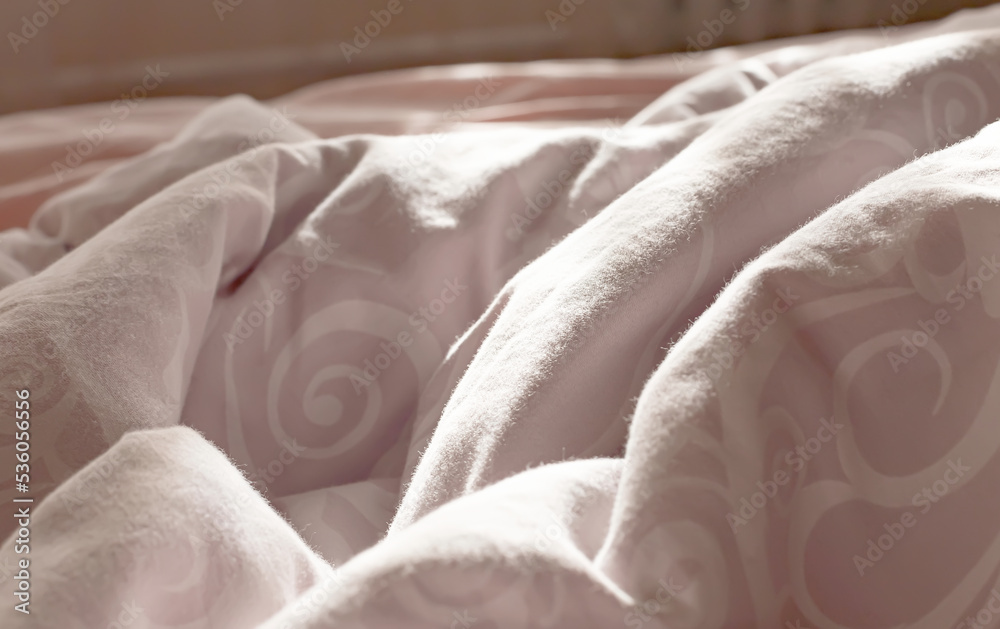 Fototapeta premium View of an unmade bed in a hotel bedroom with a crumpled sheet, duvet/duvet and pillows after waking up in the morning. Lack of tucked bed linen to sleep in.