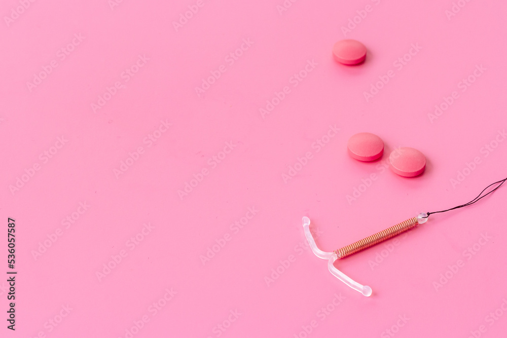 Contraception concept. T-shaped intrauterine contraceptive with medicine pills