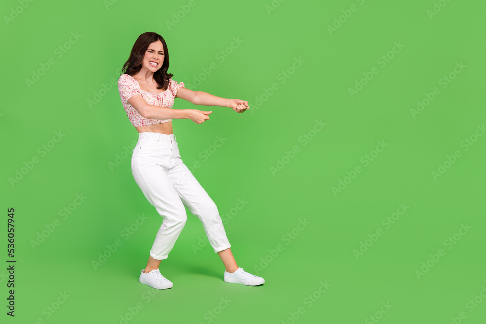 Full body size photo of young gorgeous nice woman wear top knot funny grimace trying hard difficult empty space ad isolated on green color background Full body size photo of young gorgeous nice woman wear top knot funny grimace trying hard difficult empty space ad isolated on green color background