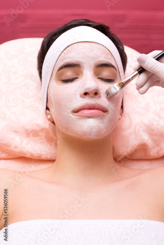 Young woman getting facial mask skin treatment in professional beauty salon