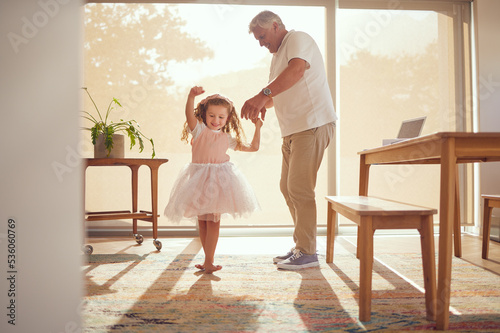 Family, young girl and grandfather dancing in living room together. Grandparent and grandchild in family home doing dance and having fun in the morning. Old man enjoying retirement with child at home