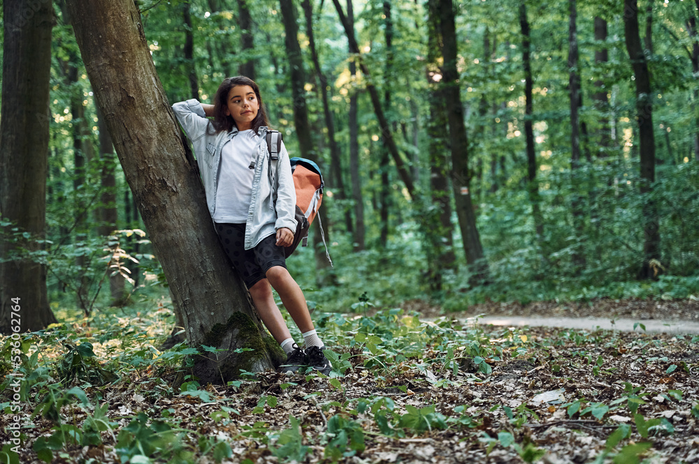 Leaning on the tree. Girl is in the forest at summer day time discovering new places Leaning on the tree. Girl is in the forest at summer day time discovering new places