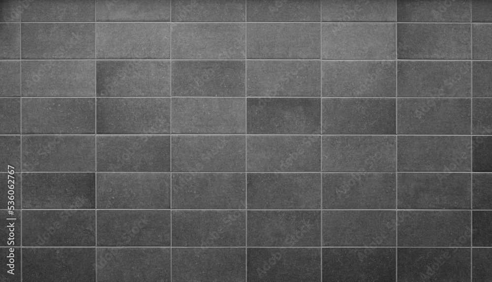Front view of a new and modern wall or building exterior made of gray slabs. Abstract full frame background in black and white. Front view of a new and modern wall or building exterior made of gray slabs. Abstract full frame background in black and white.