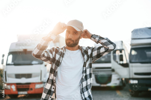 Standing against beautiful sunlight. Young truck driver is with his vehicle at daytime photo