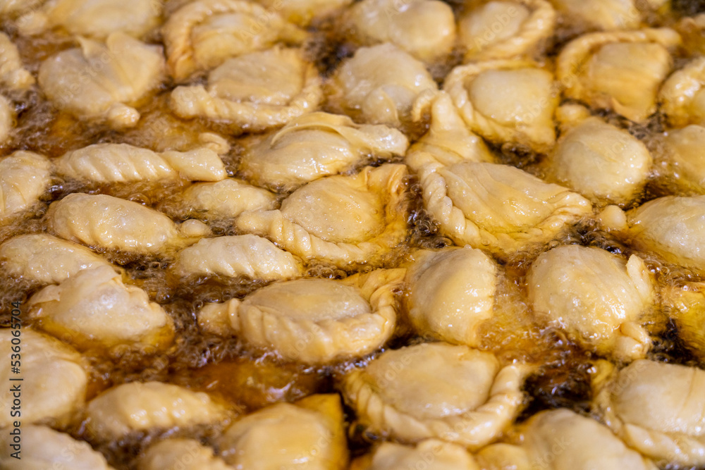 Curry puffs are being fried in a stainless steel pot. Curry puffs are being fried in a stainless steel pot.
