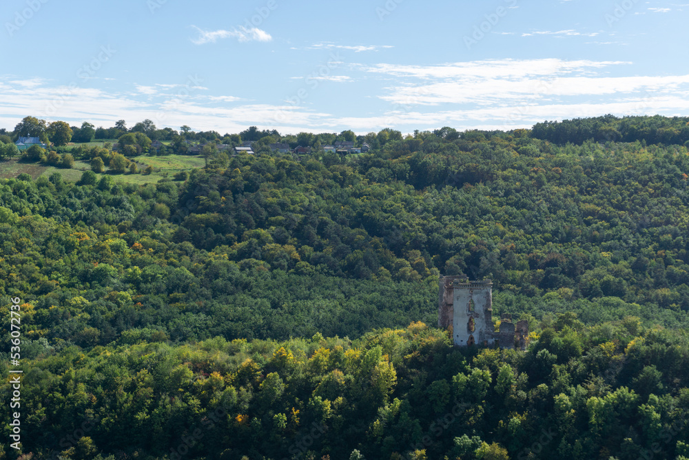 Naklejka premium Ruins of the old castle on the hill hugged by autumn forest.