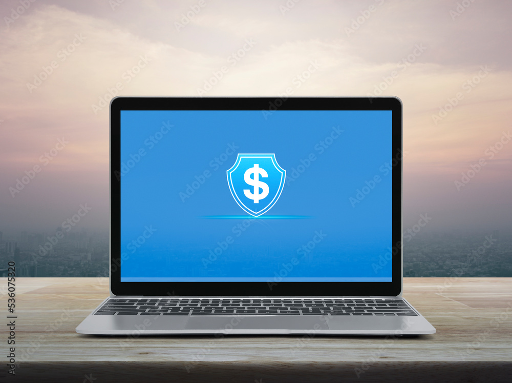 Dollar with shield flat icon on modern laptop computer monitor screen on wooden table over office city tower and skyscraper at sunset sky, vintage style, Business money insurance and protection online Dollar with shield flat icon on modern laptop computer monitor screen on wooden table over office city tower and skyscraper at sunset sky, vintage style, Business money insurance and protection online