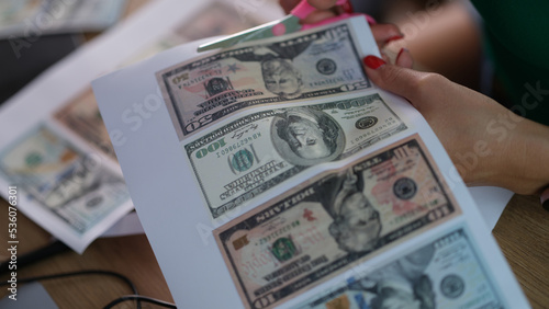 Counterfeiter cuts dollar bills with scissors closeup photo