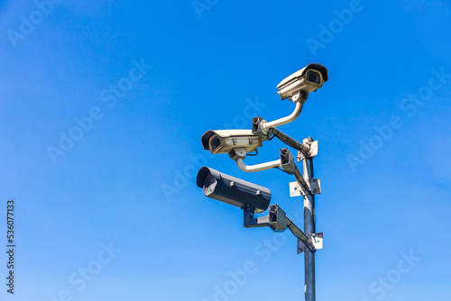 Old security camera or CCTV sits on a pole with a sky background.