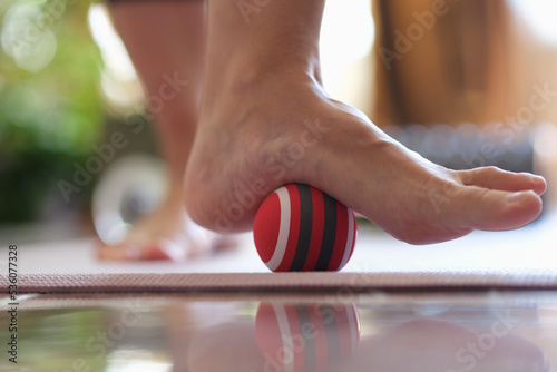 Person rolls ball on foot at home closeup