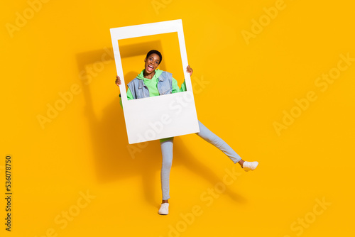 Full length body size view of attractive cheerful funky girl holding frame having fun dancing isolated over bright yellow color background