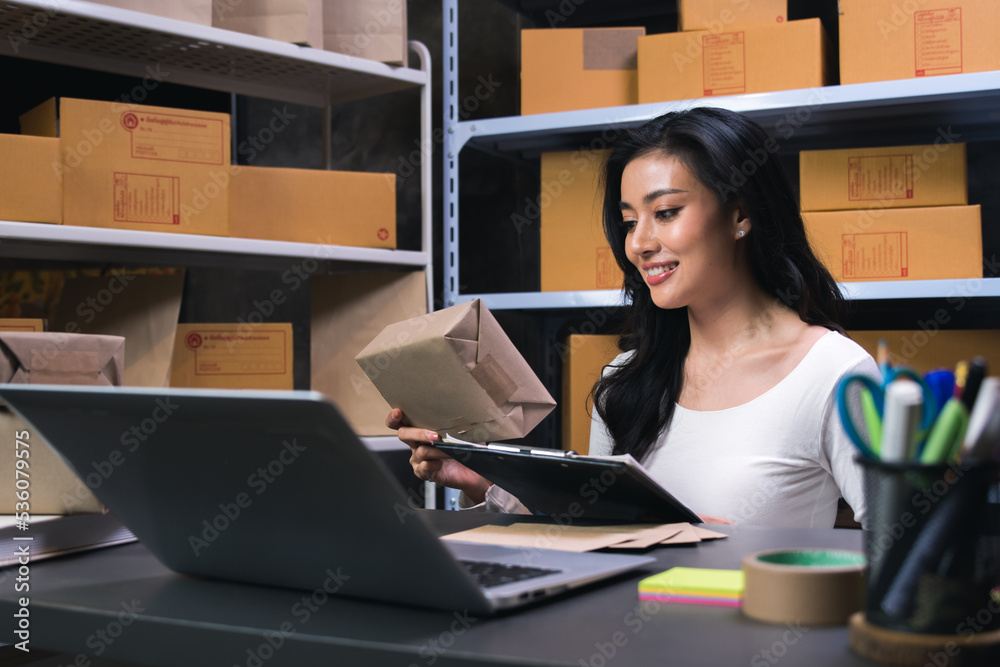 young Asian businesswoman owner runs e-commerce, prepares parcels and checks orders to deliver to customers on his laptop at home. Sell products online through the Internet, online business concept young Asian businesswoman owner runs e-commerce, prepares parcels and checks orders to deliver to customers on his laptop at home. Sell products online through the Internet, online business concept