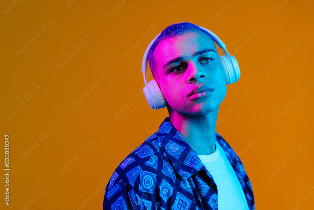 Young handsome stylish serious boy in headphones looking aside
