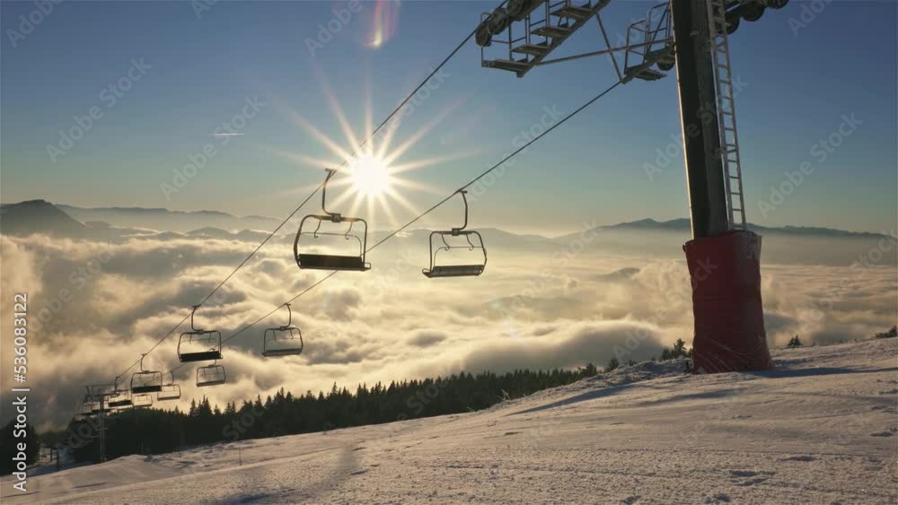 Sunny morning in winter season background in mountains ski resort with empty chairlift in beautiful nature at sunrise