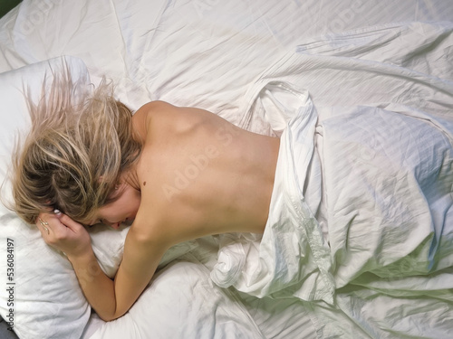 A young naked girl sleeps in bed. Early morning. Dream.