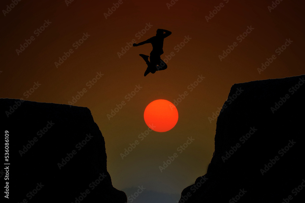 silhouette of man jumping over the cliff on sun background, business concept idea