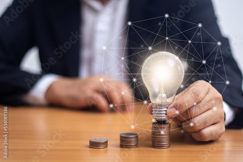 Businessman holding a light bulb on a coin (business growth concept)