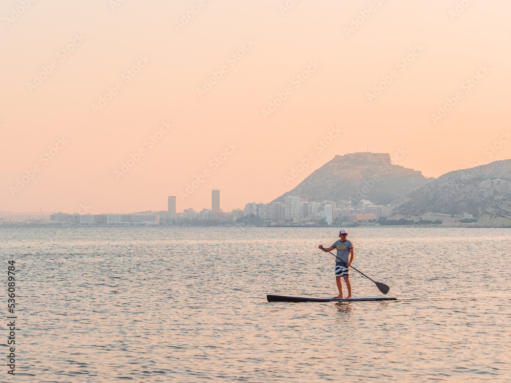 Man with paddle on surfboard on high seas Man with paddle on surfboard on high seas