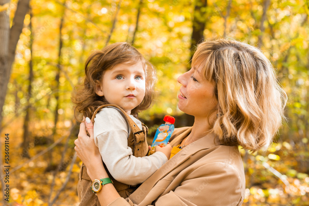 Mother with child in her arms against background of autumn nature. Family and season concept. Mother with child in her arms against background of autumn nature. Family and season concept.