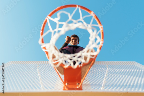 Black player standing on basketball hoop with a clenched fist photo