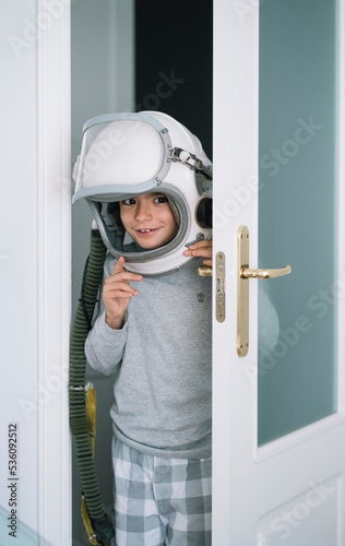 Adorable kid with helmet looking through the crack in the door photo