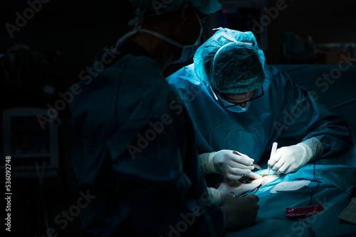 Unrecognizable surgeons performing surgery in dark room