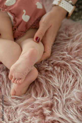 Baby's foot in mother hands closeup on pink fluffy rug , New family and baby healthy concept.