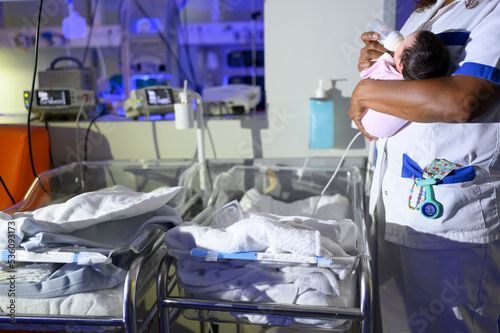 Nurse feeding newborn with milk bottle in maternity hospital photo