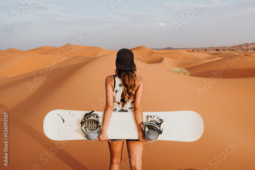 Young woman walking on sand ready for sandboarding photo