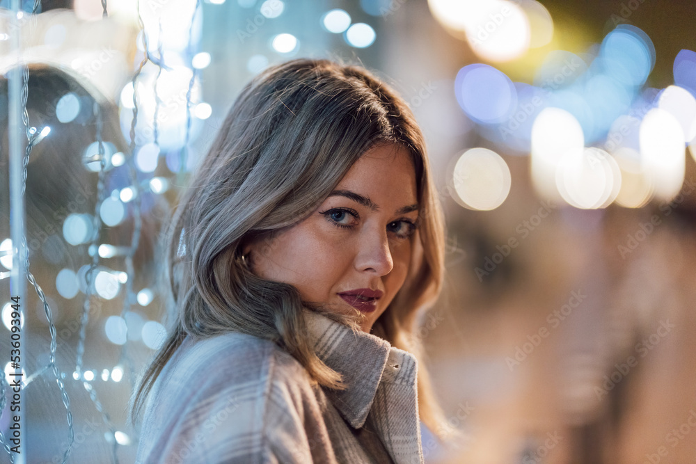 Smiling woman standing near showcase with glowing garland Smiling woman standing near showcase with glowing garland