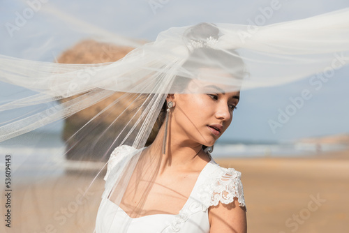 Bride in veil on shore on wedding day photo