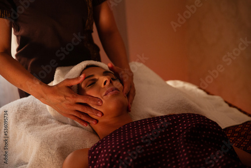 Anonymous female massagist giving a face massage to a young woman photo
