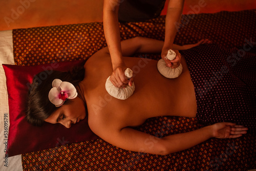 Thai female massagist giving a massage to a young woman photo