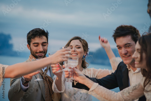 Young people in evening wear clanging glasses with drinks