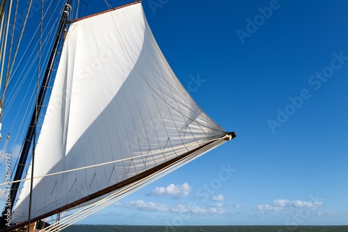 ship mast and a white sail on a blue sky