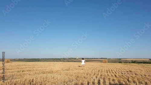 a little girl with a balloon in a field with haystacks on a sunny summer day