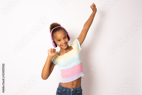 Cheerful young african american woman girl posing isolated on white background studio portrait. People lifestyle concept. Listen music with headphones, dancing