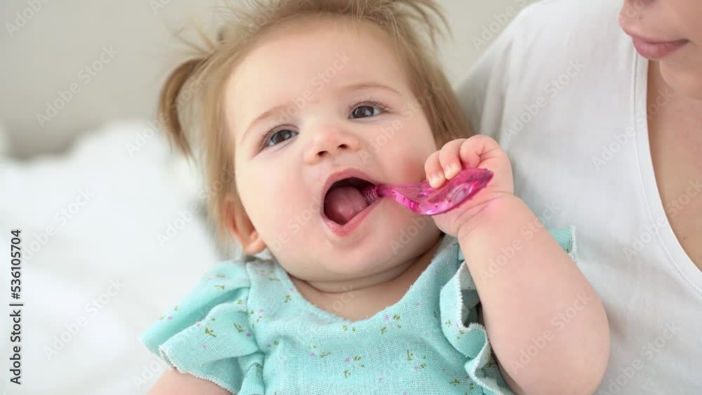 Cute baby girl is learning to brush her teeth. First toothbrush. Fun lifestyle play dentist game. Close up portrait of child trying to clean the teeth by himself. Oral dental care hygiene
