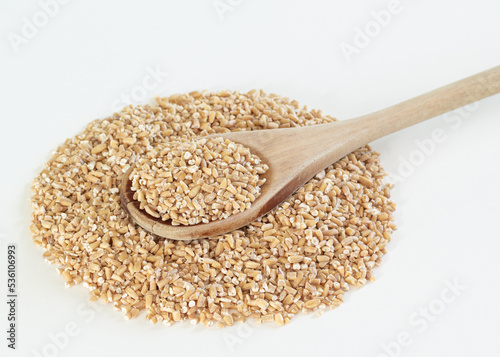 Steel cut oats and wooden spoon on white