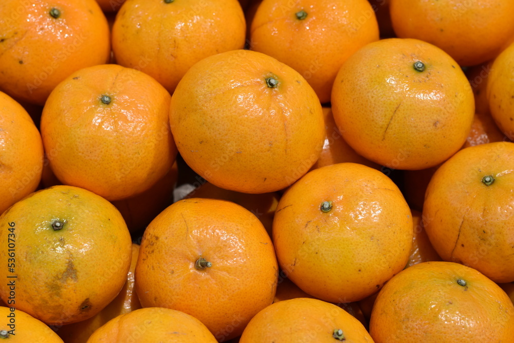 Bright orange shiny tangerines lie on a shelf in a store. Bright orange shiny tangerines lie on a shelf in a store.