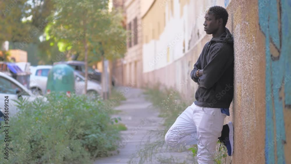 Black man looking away contemplating leaning on a wall Black man looking away contemplating leaning on a wall