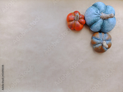 Three artificial alabaster pumpkins lie in the upper corner of a beige background for copy space