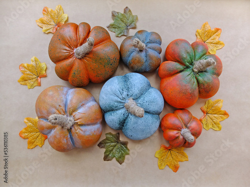 Artificial alabaster pumpkins with autumn leaves lie on the background of the craft