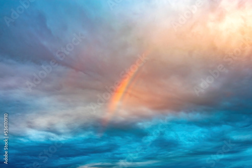 rainbow over Cumulus and cirrus cloudy dramatic gloomy sky before evening thunderstorm © welcomeinside