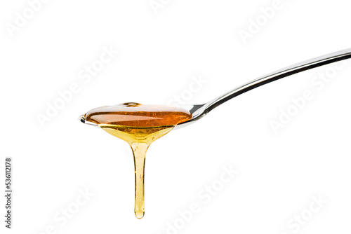 Honey dripping from spoon, isolated on white.