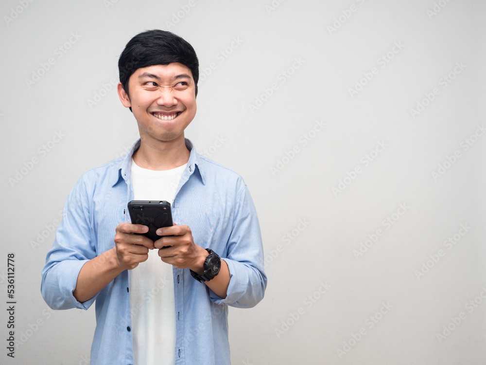 Positive man using mobile phone and smiling thinking about food feels hungry isolated Positive man using mobile phone and smiling thinking about food feels hungry isolated