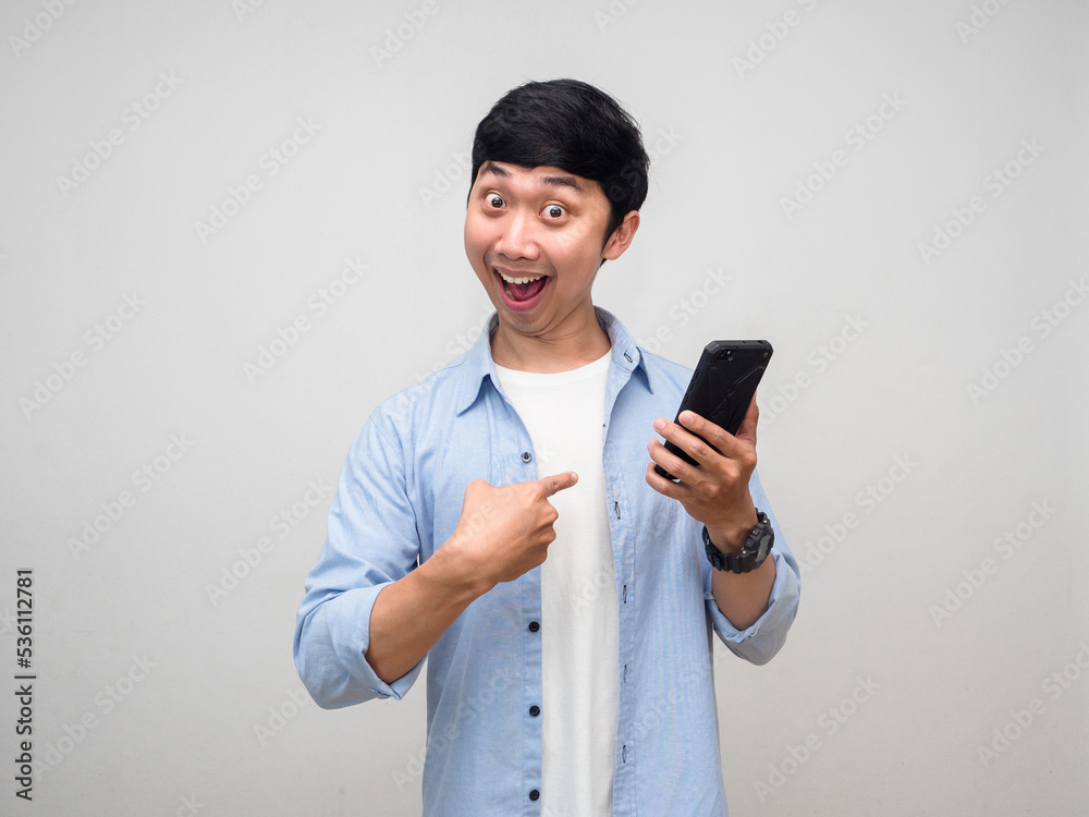 Positive asian man blue shirt hold mobile phone and point finger at himself isolated Positive asian man blue shirt hold mobile phone and point finger at himself isolated